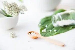 homeopathic granules, medicinal herbs on a natural wooden table on a natural background. alternative medicine and homeopathy