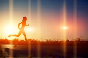 Silhouette of athletic girl running down the beautiful road