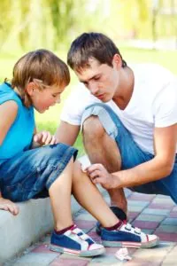 A father putting a bandage on his child's scrape.