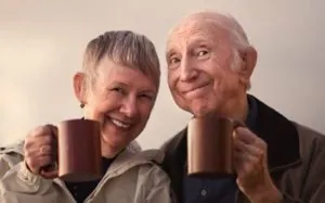 Smiling Senior Couple Toasting with Mugs