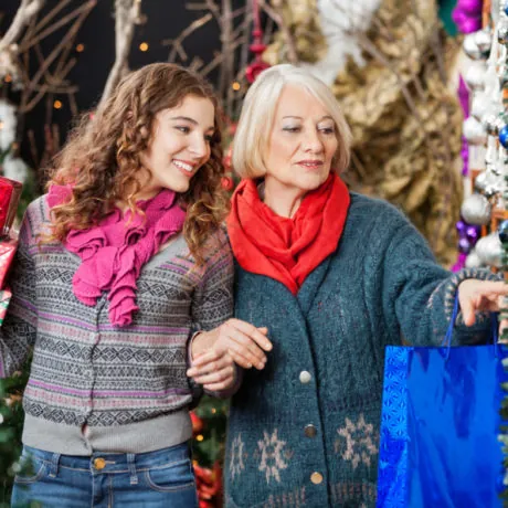 Happy mother and daughter shopping for Christmas ornaments in store