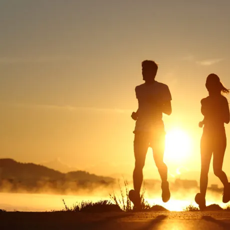 Silhouette of a couple running at sunset