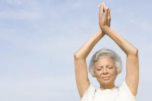 African American senior woman practicing yoga against sky