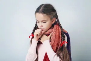 Young sick girl with scarf on grey background