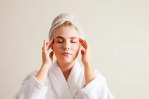 Beautiful young woman with clean perfect skin doing facial self- massage at home