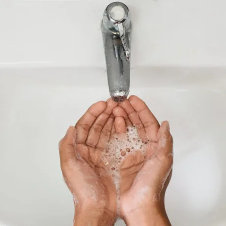 top view of a boy cupped soapy hand against washbasin. Concept of a hand hygiene and global handwashing day
