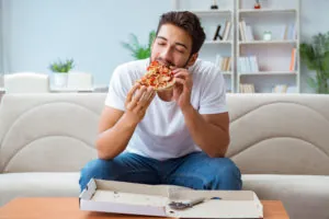 Man eating pizza having a takeaway at home relaxing resting