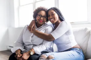 affectionate mother and daughter sitting on sofa