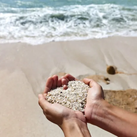 Mellow heart shaping female hands at beach