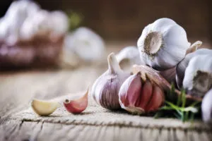 Garlic cloves on rustic table. Garlic in wooden bowl. Fresh peeled garlic and bulbs.