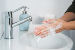 Hygiene. Cleaning Hands. Washing hands with soap. Young woman washing hands with soap over sink in bathroom, closeup. Covid 19. Coronavirus.