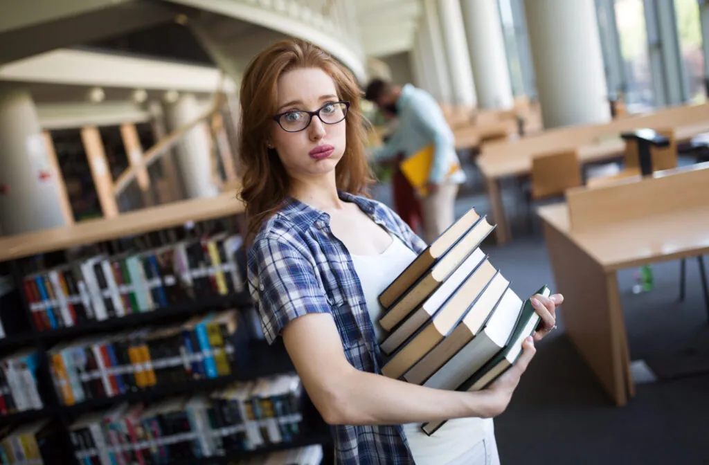 Frustrated teen student girl with a lot of books