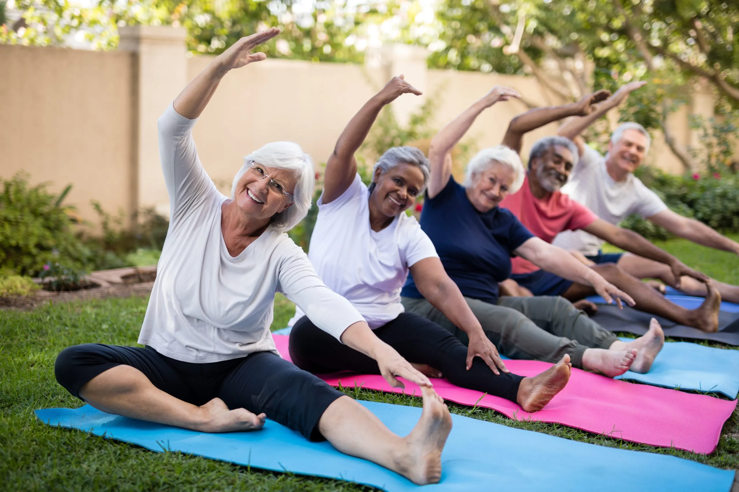 Portrait of smiling senior friends exercising at park