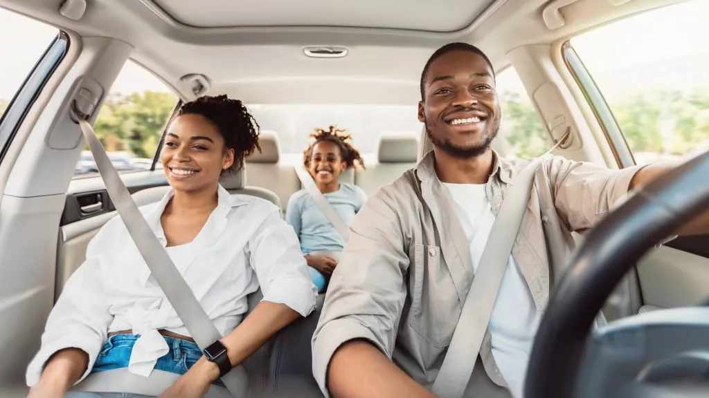 Happy African American Family Riding Car Traveling By Automobile. Black Parents And Daughter Enjoying Summer Road Trip Together On Weekend. Panorama, Selective Focus