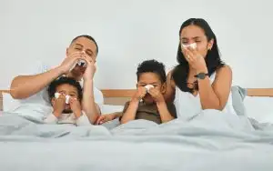 Shot of a family blowing their noses while sick in bed at home.