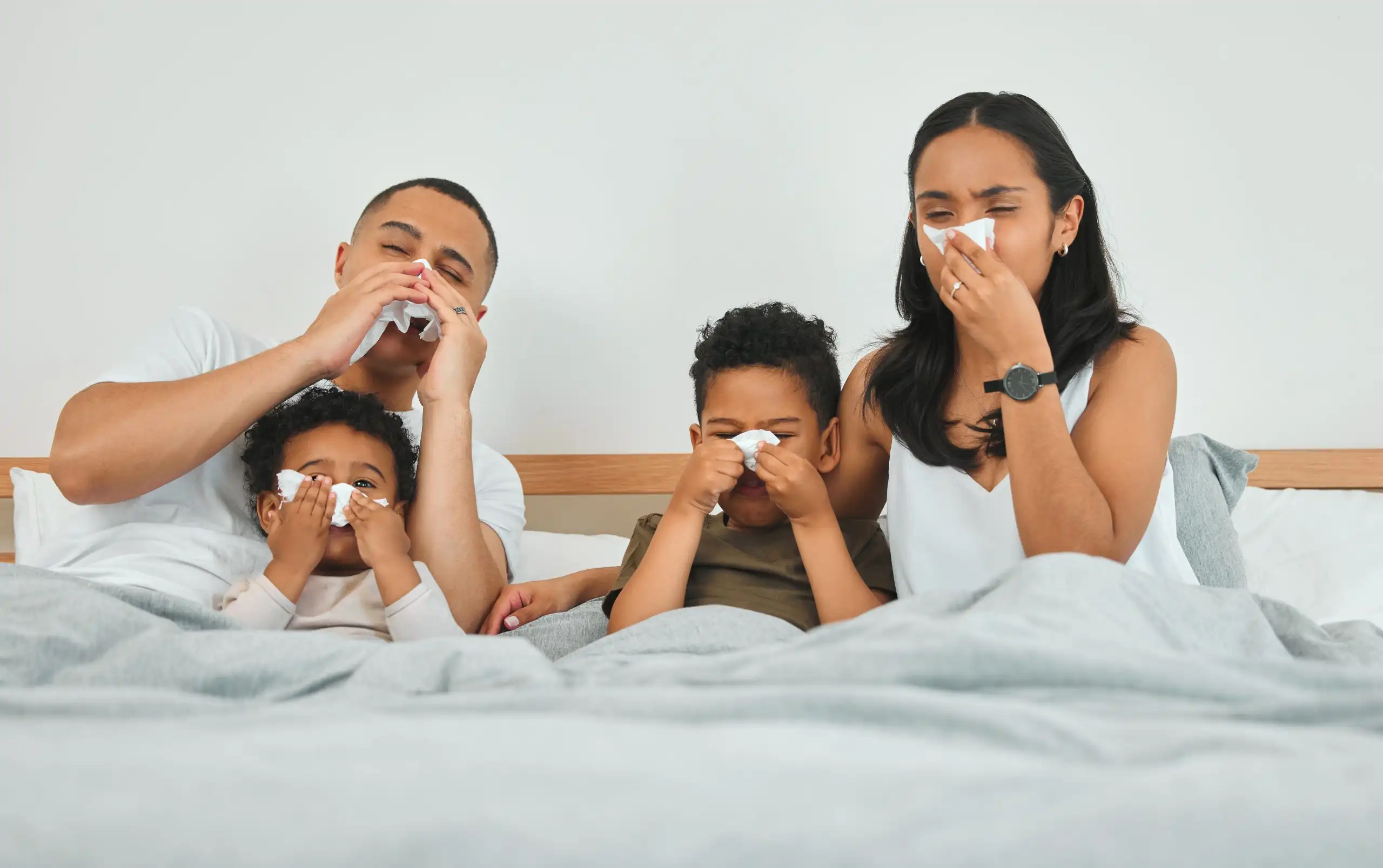 Shot of a family blowing their noses while sick in bed at home.