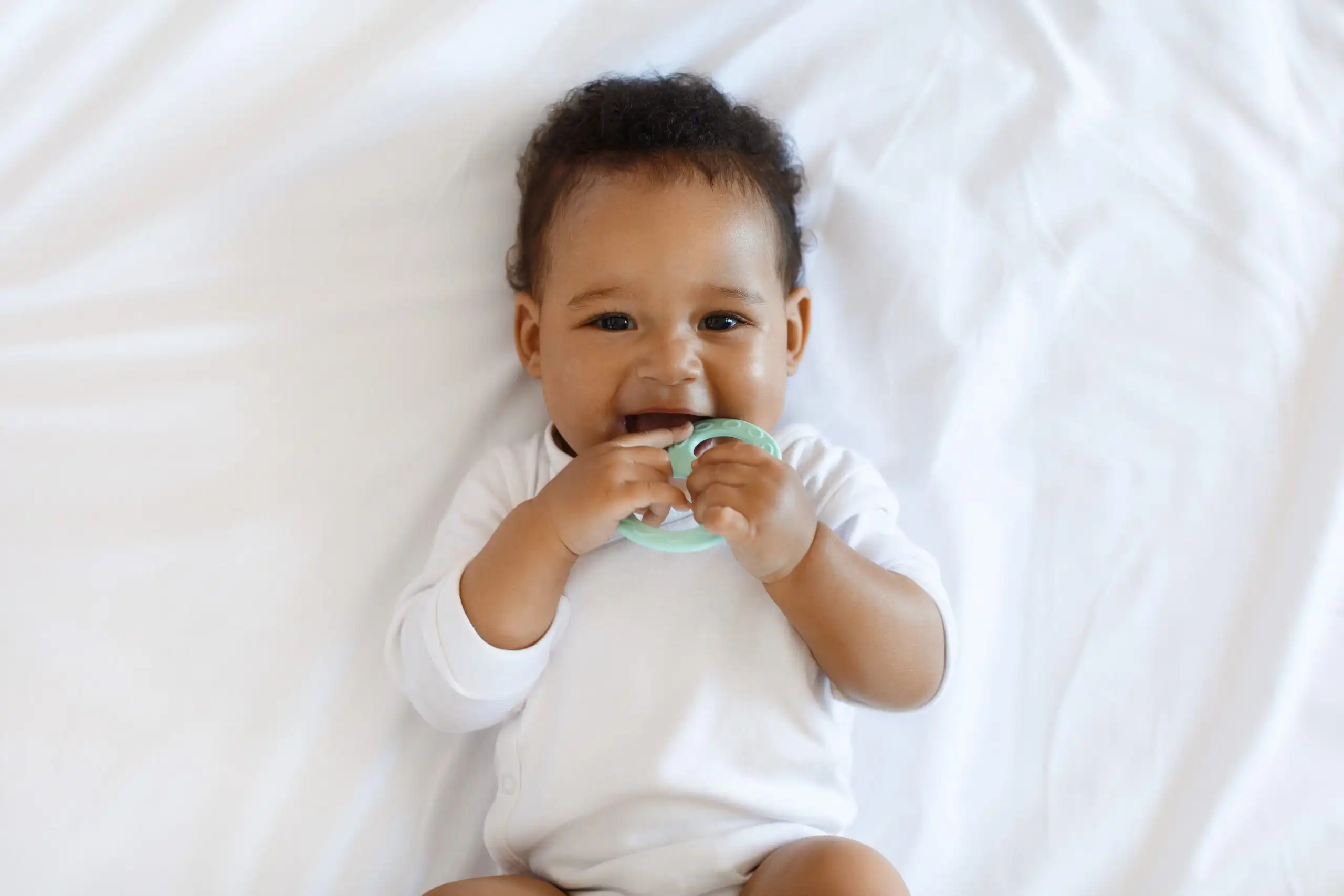 Adorable African American Baby Biting Teether And Looking At Camera