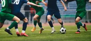 Soccer football player dribbling a ball and kick a ball during match in the stadium. Footballers in action on the tournament game. Adult football competition