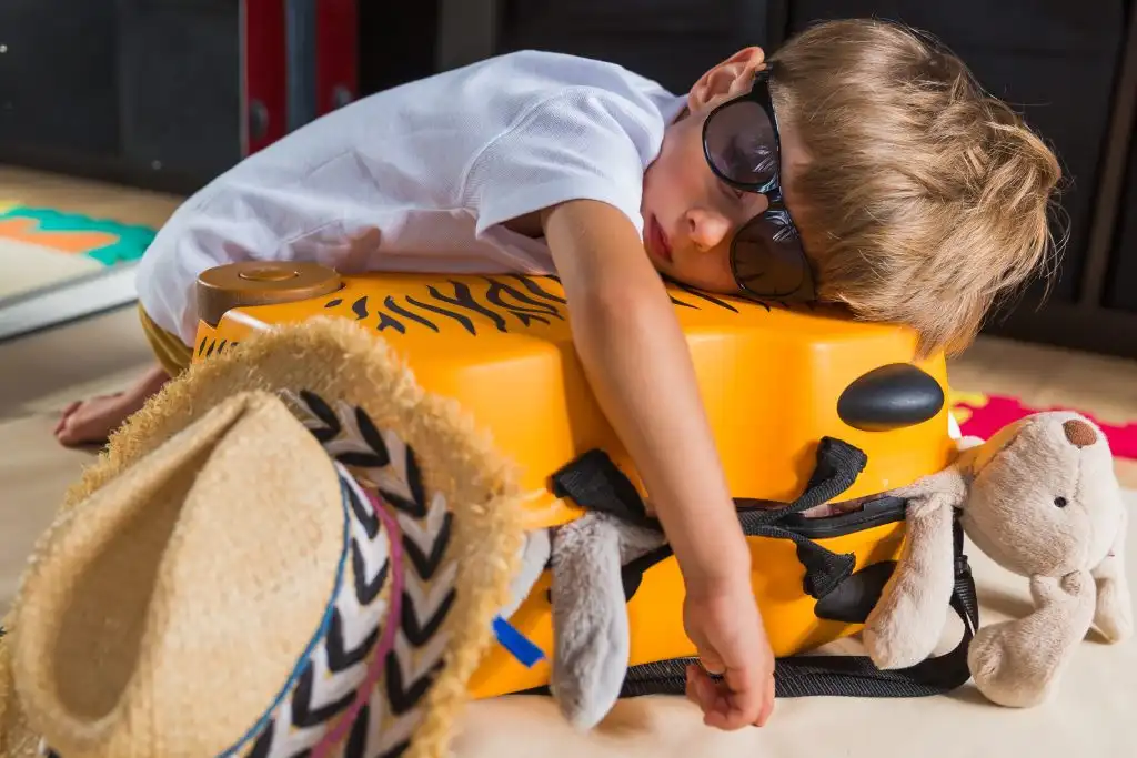 Handsome boy fall asleep on a suitcase. Suitcase with things, Teddy. Travel.