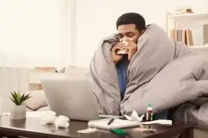 Sick man working from home on the couch